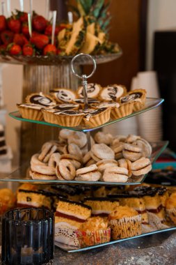 Meyveli turtalar, kurabiyeler ve çikolata kaplı mini kekler de dahil olmak üzere çok güzel düzenlenmiş hamur işleri sofistike bir etkinlikte servis standında sunuldu.
