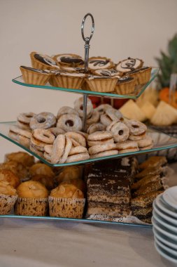 Davetkar bir yukarıdan çekim, içinde mini turtalar, kurabiyeler ve brovniler olan kademeli bir tatlı standı yakalar. Parti yemekleri için ideal.