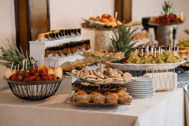 İçinde çikolatalı pastalar, taze meyve tabakları, katmanlı tezgahlar ve yumuşak ışıklandırma bulunan lüks bir tatlı masası. Düğünler, partiler, yemek servisi ya da özel günler için ideal