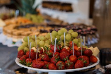 Canlı bir hayat, çikolatalı pastaların yanında çilek ve yeşil üzüm gibi çeşitli taze meyvelerle dolu zengin bir tatlı büfesi sergiliyor. Olay planlama ve yemek fotoğrafçılığı için ideal