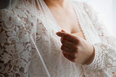 Yakın çekim, törenden önce narin dantelli peçesini nazikçe düzelten bir gelini yakalar. Romantizm, aşk ve düğün günü beklentilerini iletir.