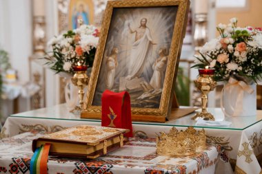 Süslü bir kilise sunağında, İsa 'nın canlı çiçek düzenlemeleri, kadeh, kitap ve tacı ile çevrili Şekil değiştirme ikonu sergilenir.