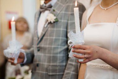 Bir düğün mum yakma töreninin yakın çekimi. Gelin beyaz elbiseli ve damat gri elbiseli. Mumları tutun. Birleşmeyi ve yeni başlangıçları temsil ediyor.