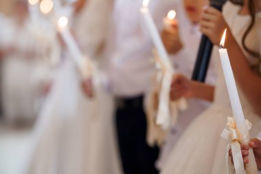 Dini tören sırasında ellerinde mum tutan beyaz komün cübbesi giymiş çocukların masumiyet ve maneviyatını yakaladıkları iç açıcı bir sahne.