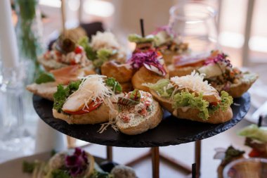 Yakın çekim bir düğün resepsiyonunda katmanlı bir tabağa dizilmiş nefis somon kanepeleri sunar, rafine aperatifleri ön plana çıkarır.