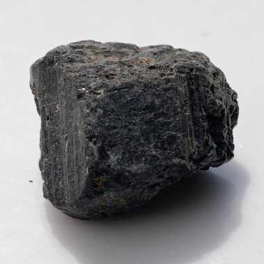 Kaba, işlenmemiş siyah bir turmalin kristalinin yakın plan çekimi. Koyu rengini ve çizgili yüzeyini sergiliyor. Mücevher ve iyileştirme çalışmalarında kullanılan popüler bir mücevher.