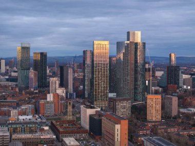 Günbatımında Deansgate Meydanı binalarının yer aldığı, Manchesters kentsel ufuk çizgisinin canlı bir görüntüsü, şehrin mimari gelişimini gözler önüne seriyor..