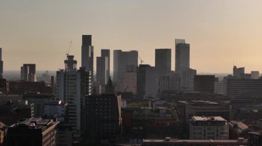 Günbatımında Manchester City Skyline: Modern Binalar, İnşaat Turnaları ve Puslu Gökyüzü