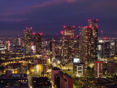 Manchester 'ın kentsel ufuk çizgisi, alacakaranlıkta aydınlatılan modern gökdelenleri vurguluyor, canlı şehir hayatı ve dinamiklerini gözler önüne seriyor.