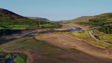 Sersemletici hava görüntüleri kuraklığın Derbyshire 'daki Woodhead Reservoir' daki etkisini gözler önüne seriyor. Düşük su seviyeleri ve kuru zemin ortaya çıkıyor. Bu kavrulmuş manzara, iklim değişikliği endişelerini vurguluyor.