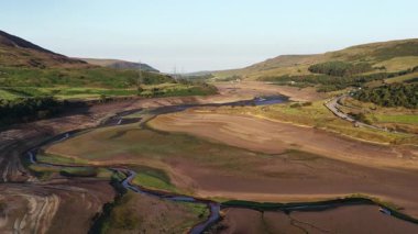 Sersemletici hava görüntüleri kuraklığın Derbyshire 'daki Woodhead Reservoir' daki etkisini gözler önüne seriyor. Düşük su seviyeleri ve kuru zemin ortaya çıkıyor. Bu kavrulmuş manzara, iklim değişikliği endişelerini vurguluyor.