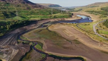 Sersemletici hava görüntüleri kuraklığın Derbyshire 'daki Woodhead Reservoir' daki etkisini gözler önüne seriyor. Düşük su seviyeleri ve kuru zemin ortaya çıkıyor. Bu kavrulmuş manzara, iklim değişikliği endişelerini vurguluyor.