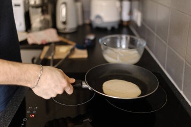Sıcak tavayla krep hazırlayan bir adamın yakın plan fotoğrafı. Yemek pişirme kavramı 