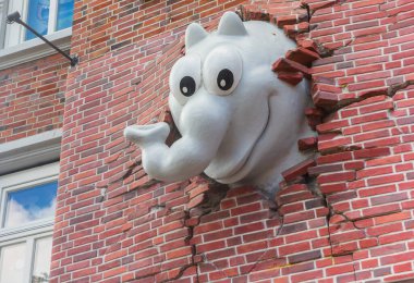 Comic book elephant breaking through the wall od the historic Otto house in Emden, Germany clipart