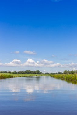 Clouds reflecting in the tranquil water of the vecht river near Gramsbergen, Netherlands clipart