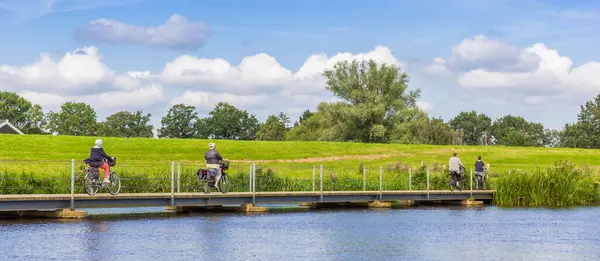 stock image Panorama of people crossing a bridge at the Vecht river on bicycle near Hardenberg, Netherlands