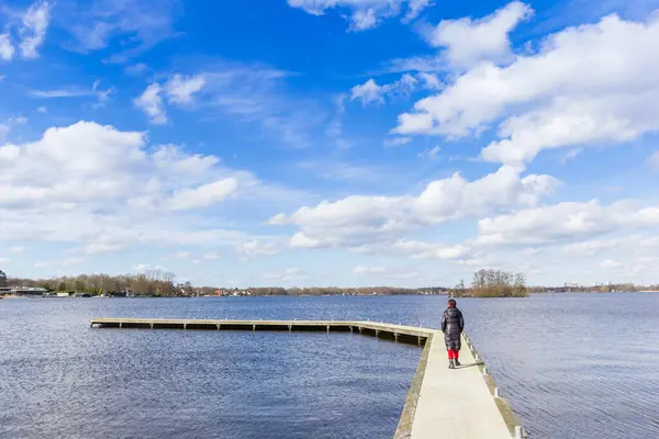 stock image Woman in winter coat walking the jetty at the lake in Paterswolde, Netherlands