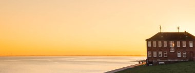 Panorama of sunset colors over the sea and dike in Wilhelmshaven, Germany clipart