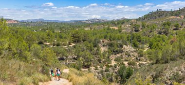 Panorama of people walking the Ruta de los Calderones path in Chulilla, Spain clipart