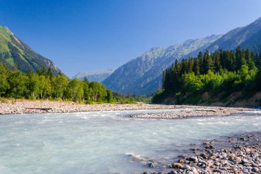 A fast and powerful river flows in a valley in the Caucasus mountains.
