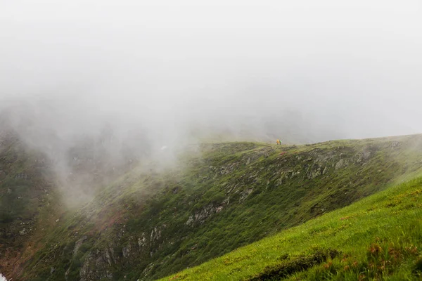两个游客在雾中爬上一座山 免版税图库图片