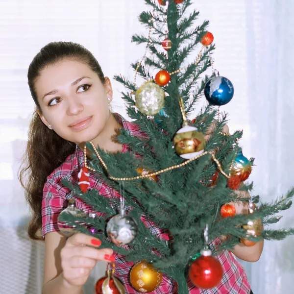 装饰圣诞树在客厅里的积极的黑发女孩 — 图库照片