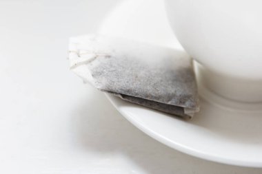Çay poşeti çay fincanının üzerinde, lezzetli kokulu çay demlemek için kaynar su bardağının yanında.