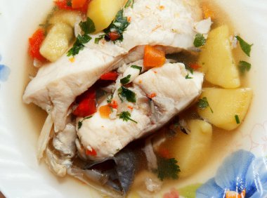 Traditional delicious savory fish soup served hot on a plate for lunch with plenty of fish mea
