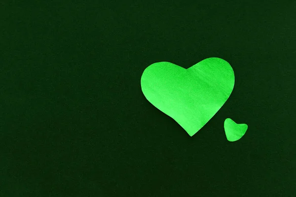 Green heart on a dark green background, made of paper, romantic and festive beautiful symbol, background