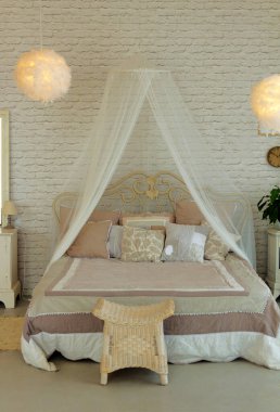 Güzel döşenmiş yatak odası, yastıklı yatak ve hafif tonlu keltoş.