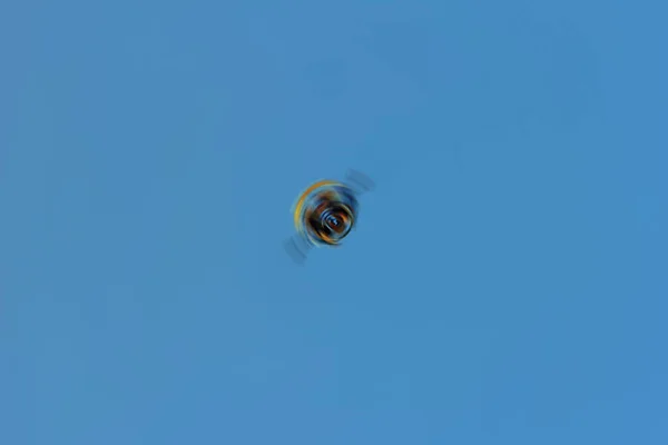青い空に回転する正体不明の飛行色の物体の概念抽象化 — ストック写真