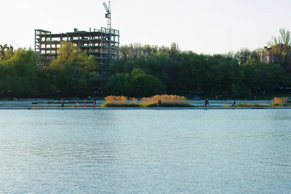在人们步行的公园区建造一座多层楼房 那里有一个湖泊和绿树 — 图库照片
