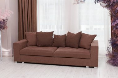 Beş yastıklı güzel kahverengi kanepe oturma odasındaki modern iç mobilyaların bir kısmını oluşturuyor.