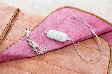 Sıcak, iki yüzlü, yeni elektrikli çarşaf bir araya getirilmiş ve çarşafın üzerinde bir ısı düğmesi ve beyaz bir çatal var. Soğuk mevsimde, kışın ısınmak için hızlı ve ekonomik bir yol.