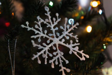 Ilık ışıkları ve bulanık bir Noel ağacı olan ışıl ışıl parlayan bir kar tanesi. Kış tatili kavramı.