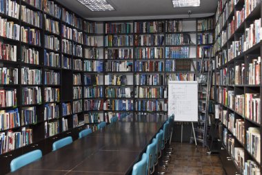 CHISINAU, MOLDOVA - 14 Mart 2025; Uzun ahşap masalar, mavi sandalyeler ve fayanslarla dolu raflar ile Eski Kütüphane iç mimarisi, eğitim ve bilgiyi simgeliyor