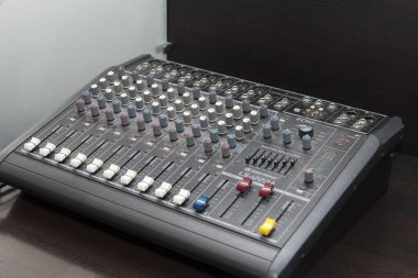 CHISINAU, MOLDOVA - 14 Mart 2025; Ses karıştırma konsolu, ses mühendisliği kurulumunu temsil eden, koyu ahşap bir yüzey üzerinde gerçekçi tarzda yakalanan çeşitli düğmeler ve kaydıraklarla