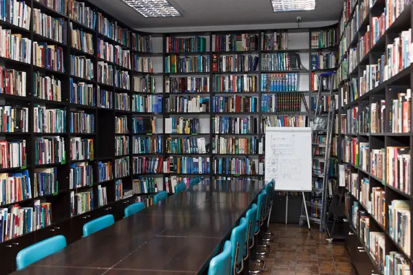 CHISINAU, MOLDOVA - 14 Mart 2025; Uzun ahşap masalar, mavi sandalyeler ve fayanslarla dolu raflar ile Eski Kütüphane iç mimarisi, eğitim ve bilgiyi simgeliyor