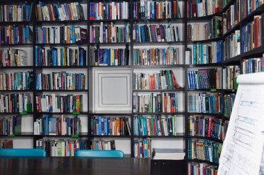 CHISINAU, MOLDOVA - 14 Mart 2025; Salonun arka planında çeşitli renkli kitaplarla dolu geniş bir kitaplık. Eğitim ve bilgi kavramı. Modern bir kütüphanenin içi