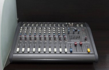 CHISINAU, MOLDOVA - 14 Mart 2025; Profesyonel Ses karıştırma konsolu, ses mühendisliği kurulumunu temsil eden, koyu ahşap bir yüzey üzerinde gerçekçi tarzda yakalanan çeşitli düğmeler ve kaydıraklarla