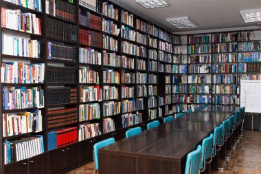 CHISINAU, MOLDOVA - 14 Mart 2025; Uzun ahşap masalar, mavi sandalyeler ve fayanslarla dolu raflarla dolu güzel kütüphane içi eğitim ve bilgiyi simgeliyor