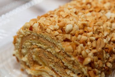 Yumuşak odaklı beyaz bir arka plana yerleştirilmiş kremalı, fındık kaplı kek rulosu. Tatlı konsepti.