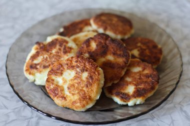 Düzgünce istiflenmiş bir tabak altın sarısı peynirli kek. Ekmeğin içi çıtır çıtır ve içi yumuşak. Dekoratif bir tabakta servis ediliyor.