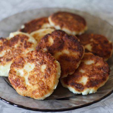 Düzgünce istiflenmiş bir tabak altın sarısı peynirli kek. Ekmeğin içi çıtır çıtır ve içi yumuşak. Dekoratif bir tabakta servis ediliyor.