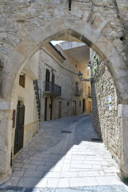 İtalya 'nın Puglia eyaletindeki bir ortaçağ köyü olan Pietramontecorvino' nun eski evleri arasında dar bir sokak..
