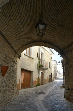 İtalya 'nın Puglia eyaletindeki bir ortaçağ köyü olan Pietramontecorvino' nun eski evleri arasında dar bir sokak..