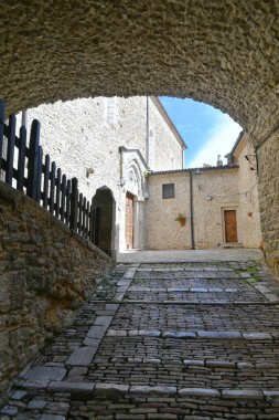 İtalya 'nın Puglia eyaletindeki bir ortaçağ köyü olan Pietramontecorvino' nun eski evleri arasında dar bir sokak..