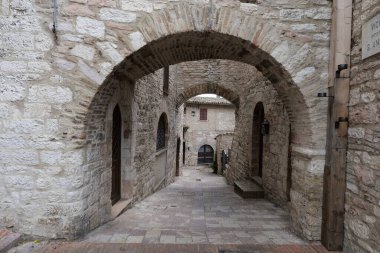 İtalya 'nın Perugia eyaletinde küçük bir ortaçağ kasabası olan Assisi' nin eski evleri arasında bir sokak..