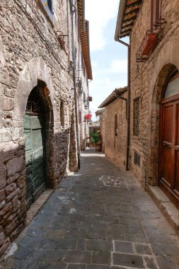 İtalya 'nın Perugia eyaletinde küçük bir ortaçağ kasabası olan Assisi' nin eski evleri arasında bir sokak..