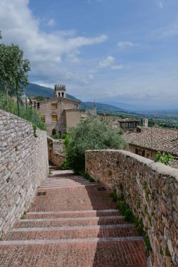 İtalya 'nın Perugia eyaletinde küçük bir ortaçağ kasabası olan Assisi' nin eski evleri arasında bir sokak..